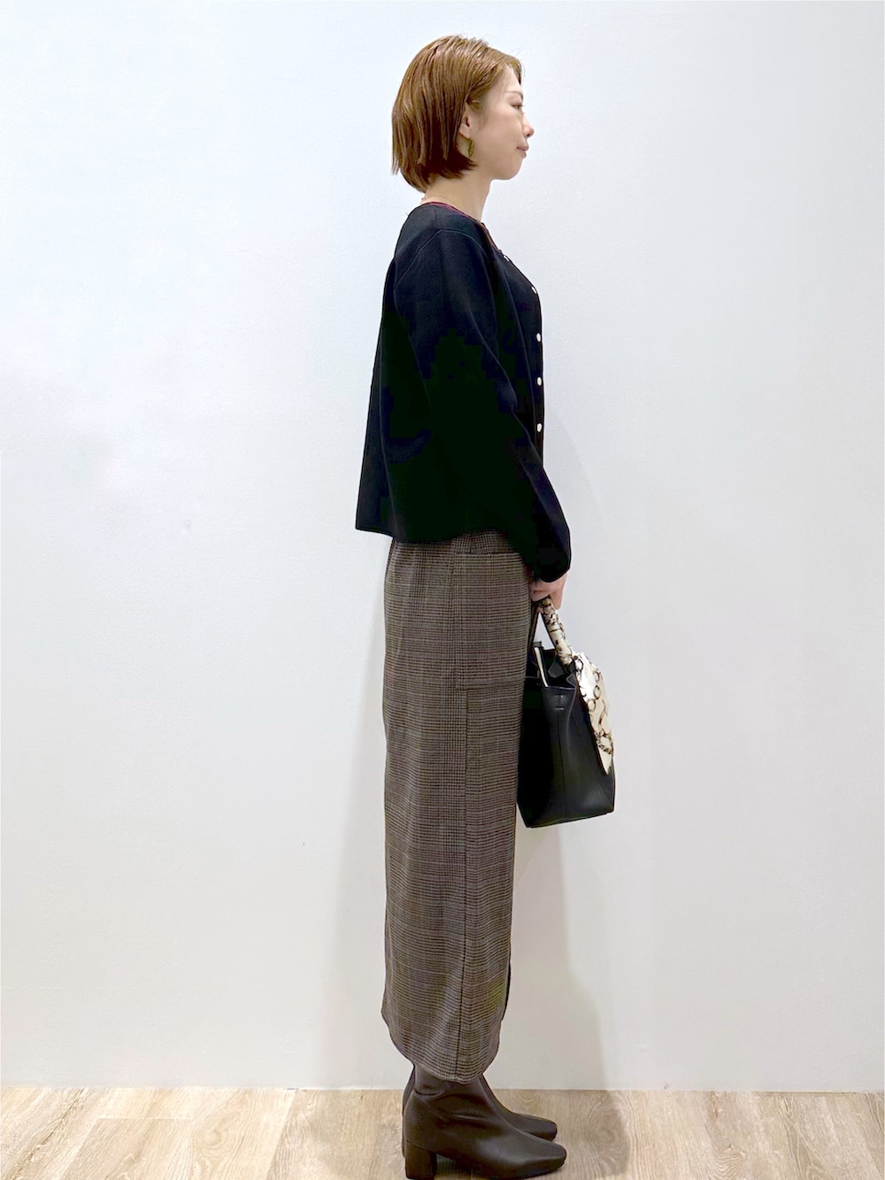ブラック系のカーディガン/ボレロ、レッド系のニット/セーター、ブラック系のトートバッグを着用したレディースの秋コーディネートの4枚目の写真