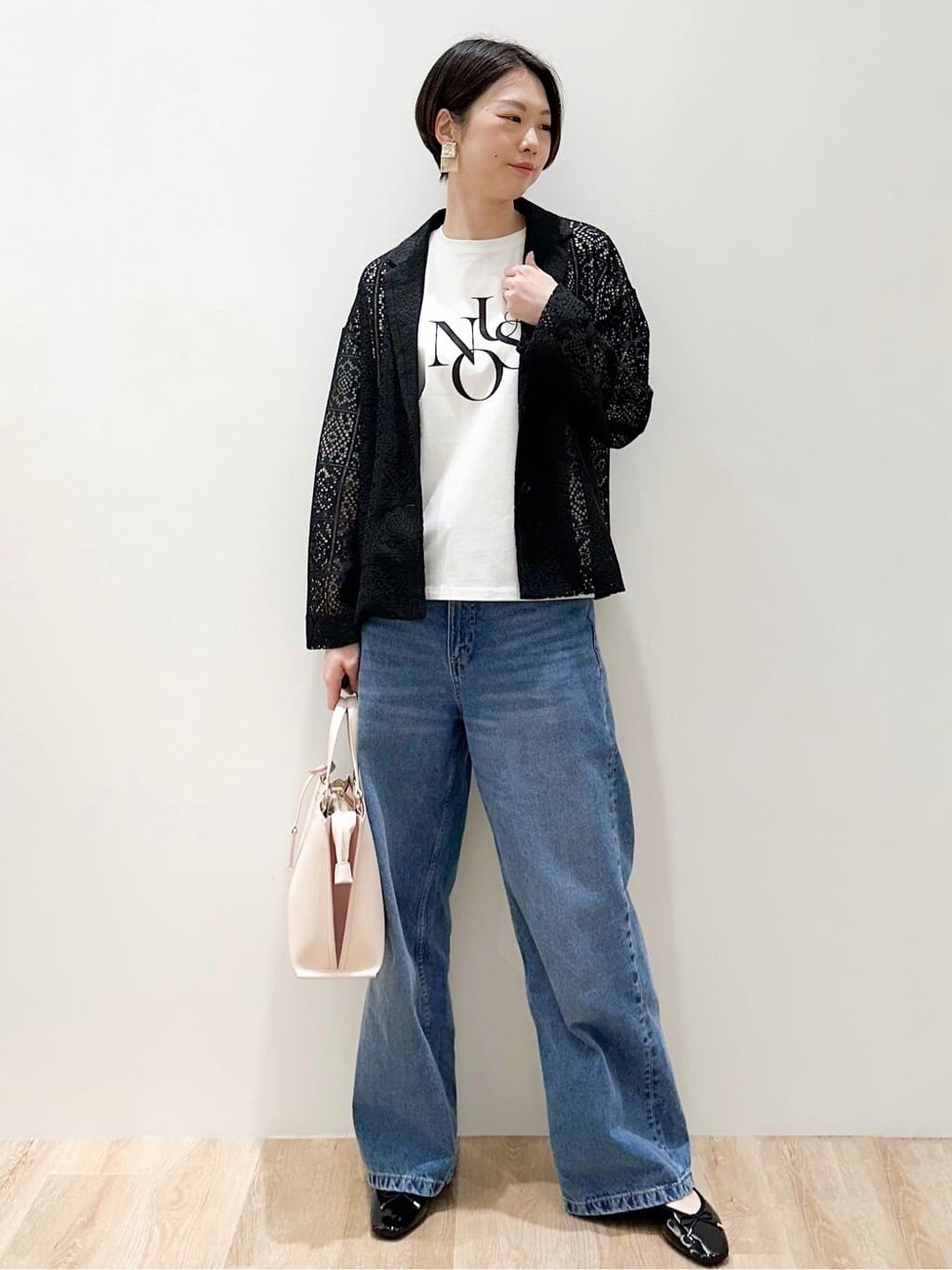 ブルー系のデニムパンツ、ブラック系のパンプス、ベージュ系のトートバッグを着用したレディースの春コーディネートの5枚目の写真