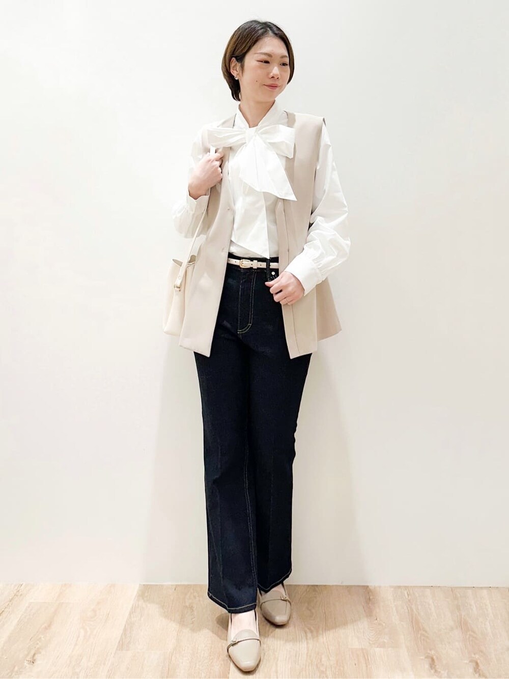 ベージュ系のベスト、ホワイト系のシャツ/ブラウス、ブルー系のデニムパンツを着用したレディースの冬コーディネートの4枚目の写真