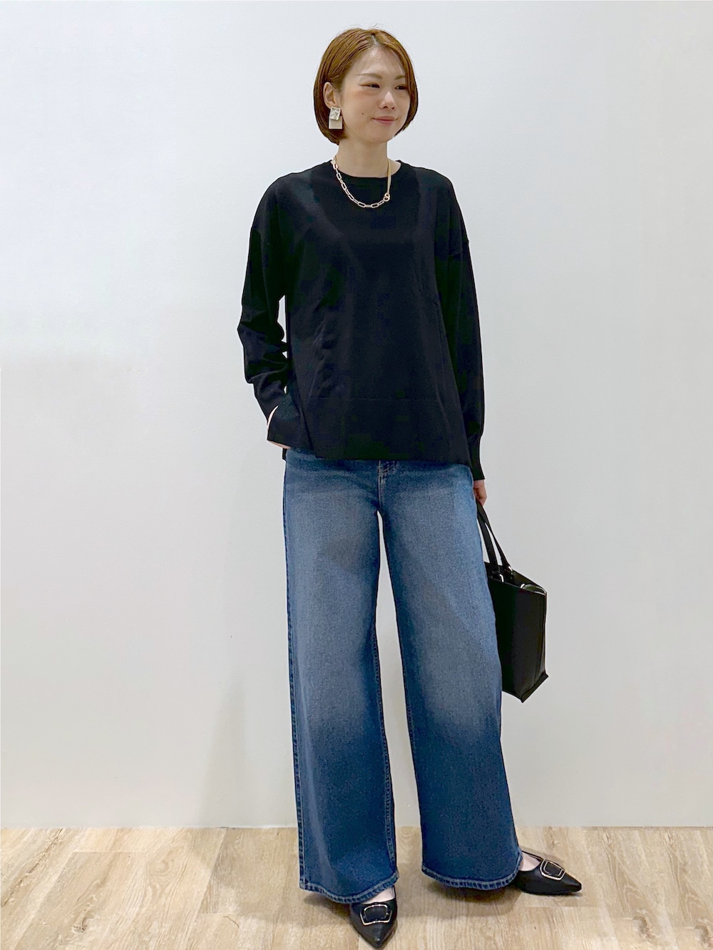 ブラック系のニット/セーター、ブルー系のデニムパンツ、ブラック系のトートバッグを着用したレディースの秋コーディネートの7枚目の写真