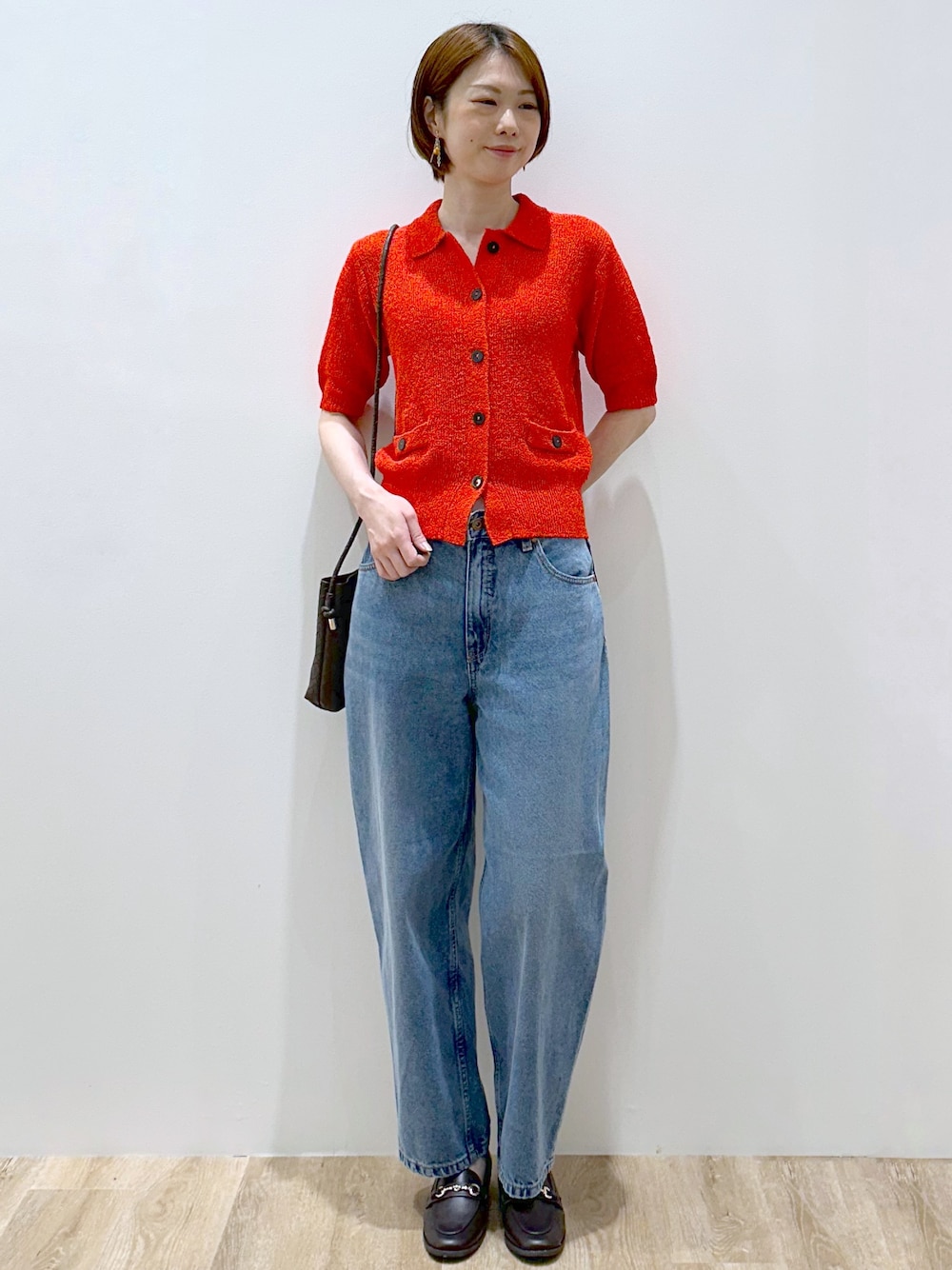 レッド系のカーディガン/ボレロ、ブルー系のデニムパンツ、ブラウン系のショルダーバッグを着用したレディースの夏コーディネートの6枚目の写真