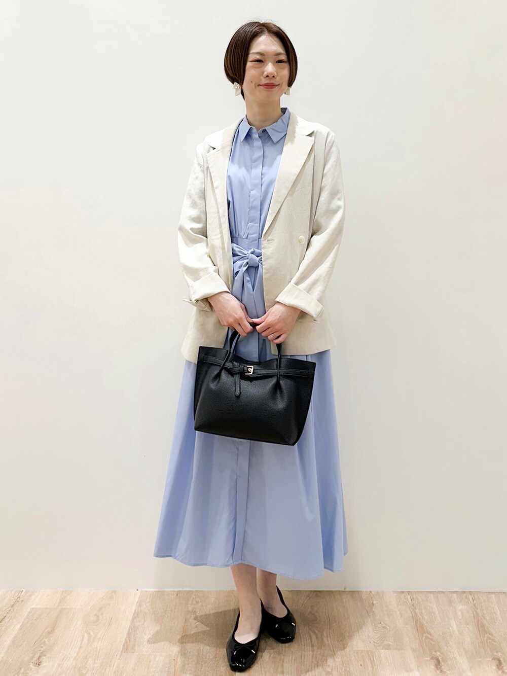 ブラック系のパンプス、ベージュ系のテーラードジャケット、ブルー系のワンピースを着用したレディースの春コーディネートの5枚目の写真