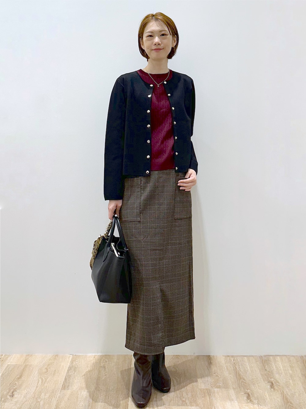 ブラック系のカーディガン/ボレロ、レッド系のニット/セーター、ブラック系のトートバッグを着用したレディースの秋コーディネートの2枚目の写真