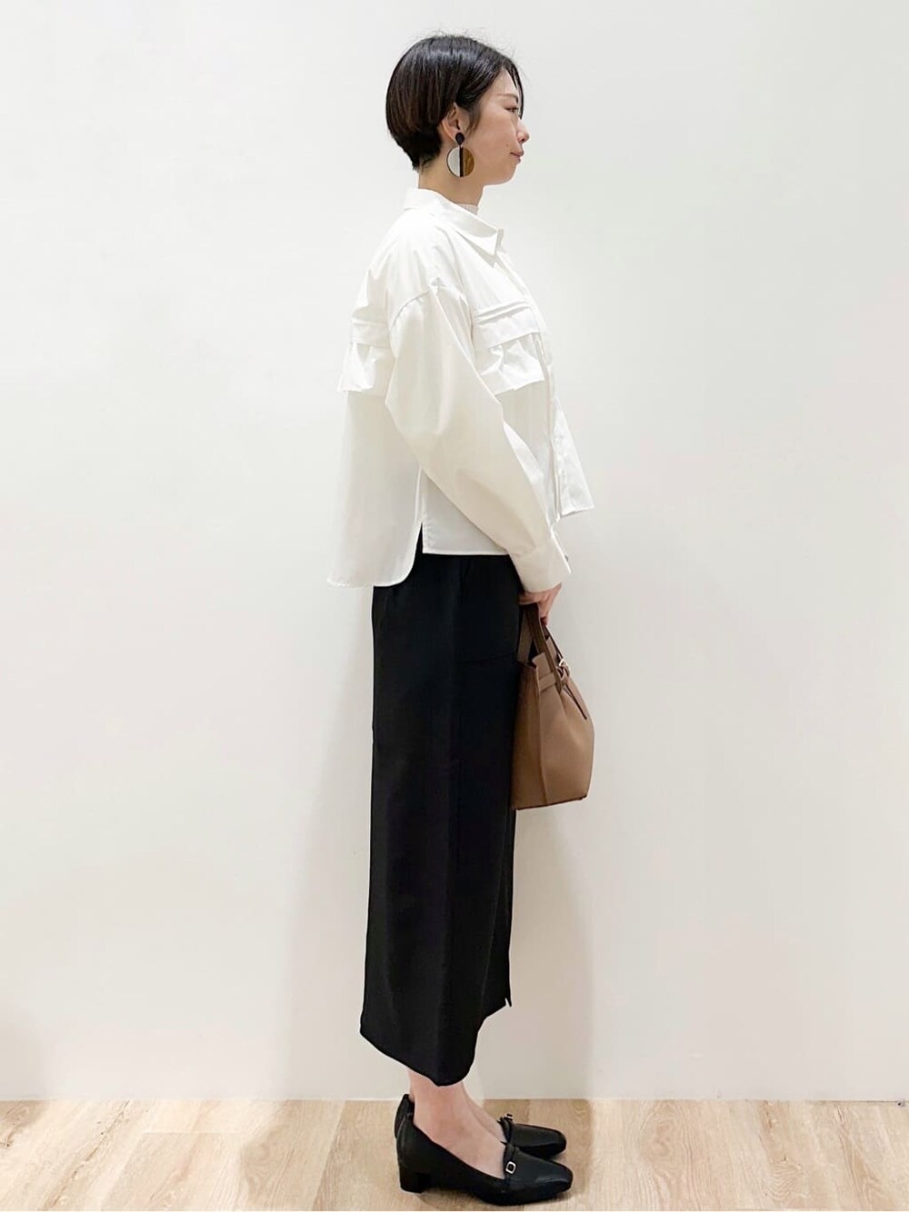 ホワイト系のシャツ/ブラウス、ホワイト系のニット/セーター、ブラック系のスカートを着用したレディースの春コーディネートの3枚目の写真