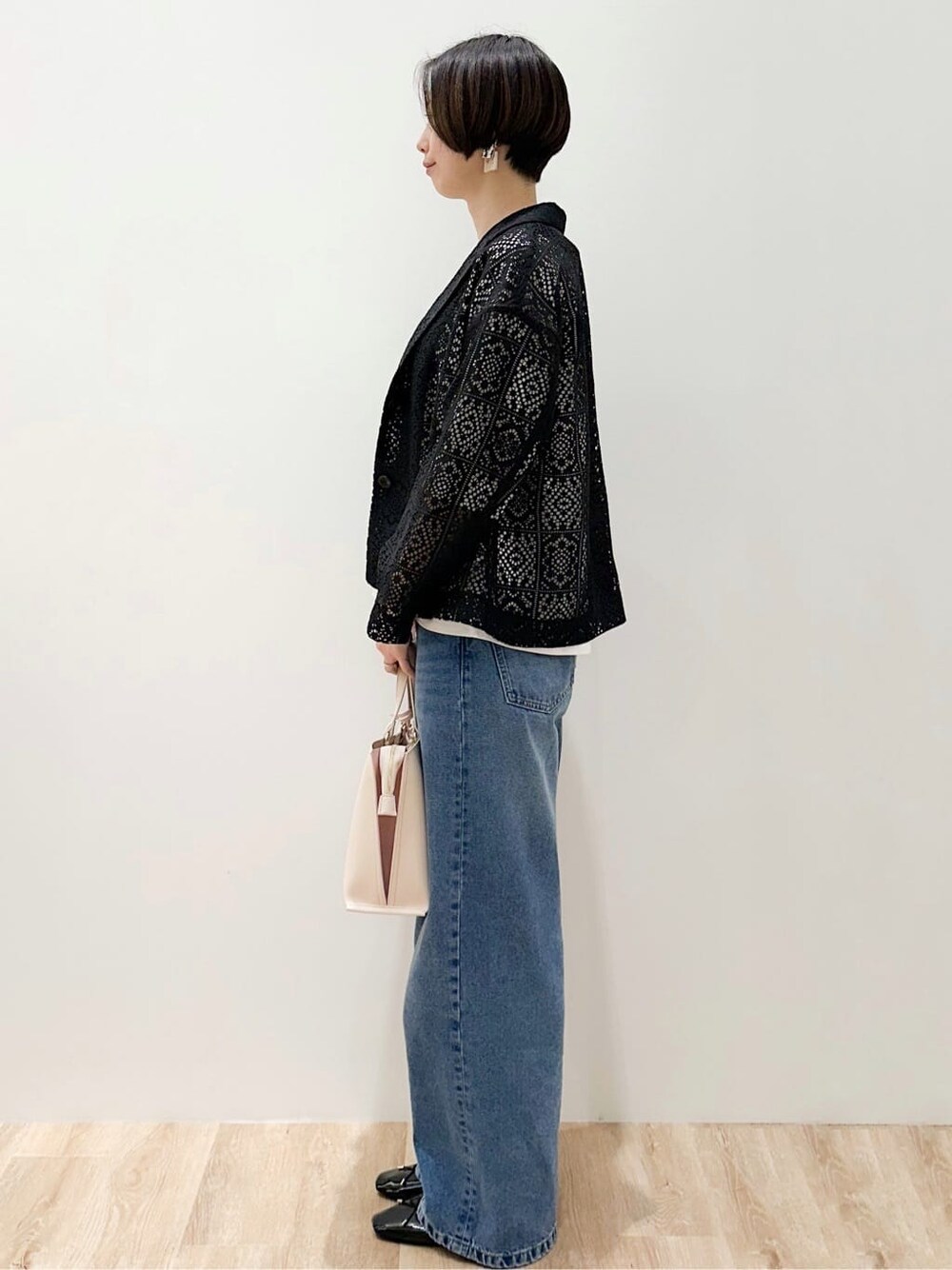 ブルー系のデニムパンツ、ブラック系のパンプス、ベージュ系のトートバッグを着用したレディースの春コーディネートの2枚目の写真