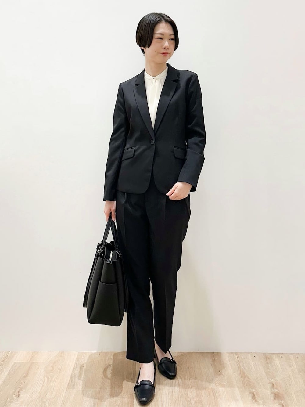 ブラック系のトートバッグ、ブラック系のパンプス、ホワイト系のシャツ/ブラウスを着用したレディースの春コーディネートの2枚目の写真