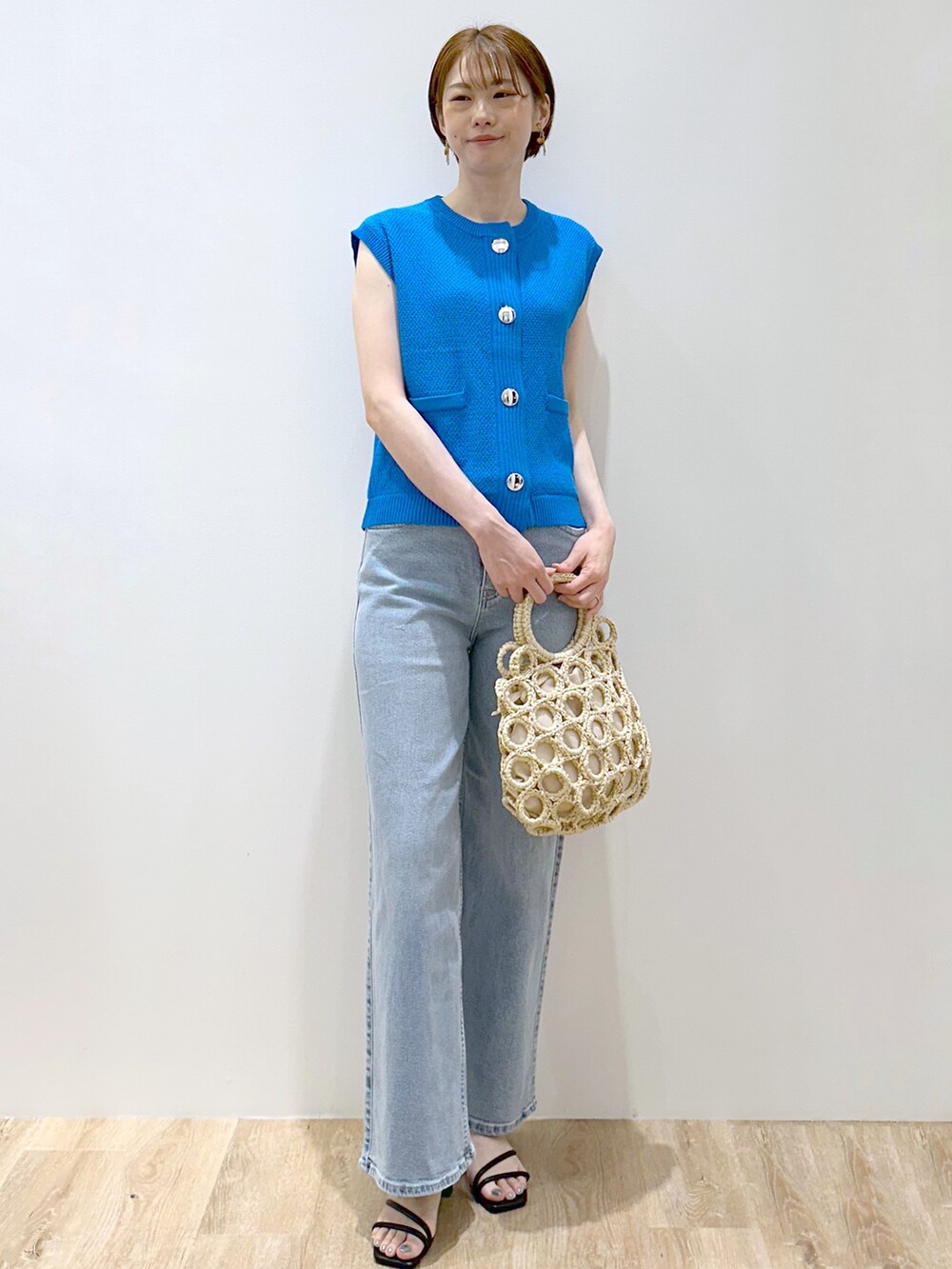 ブルー系のニット/セーター、ブルー系のデニムパンツ、ホワイト系のハンドバッグを着用したレディースの夏コーディネートの2枚目の写真