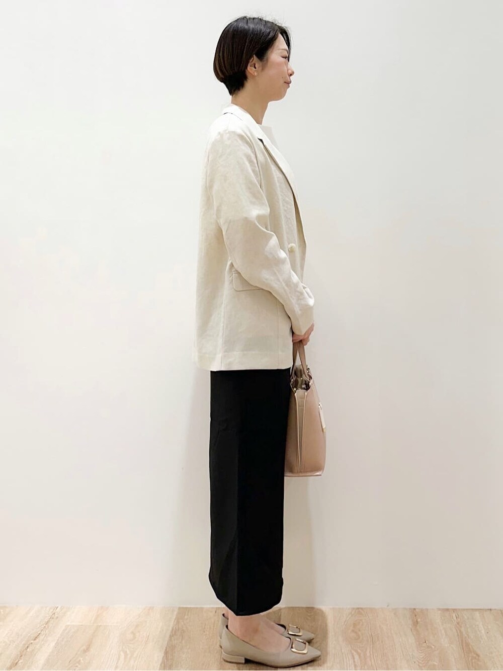 ベージュ系のパンプス、ブラック系のスカート、ベージュ系のトートバッグを着用したレディースの春コーディネートの2枚目の写真