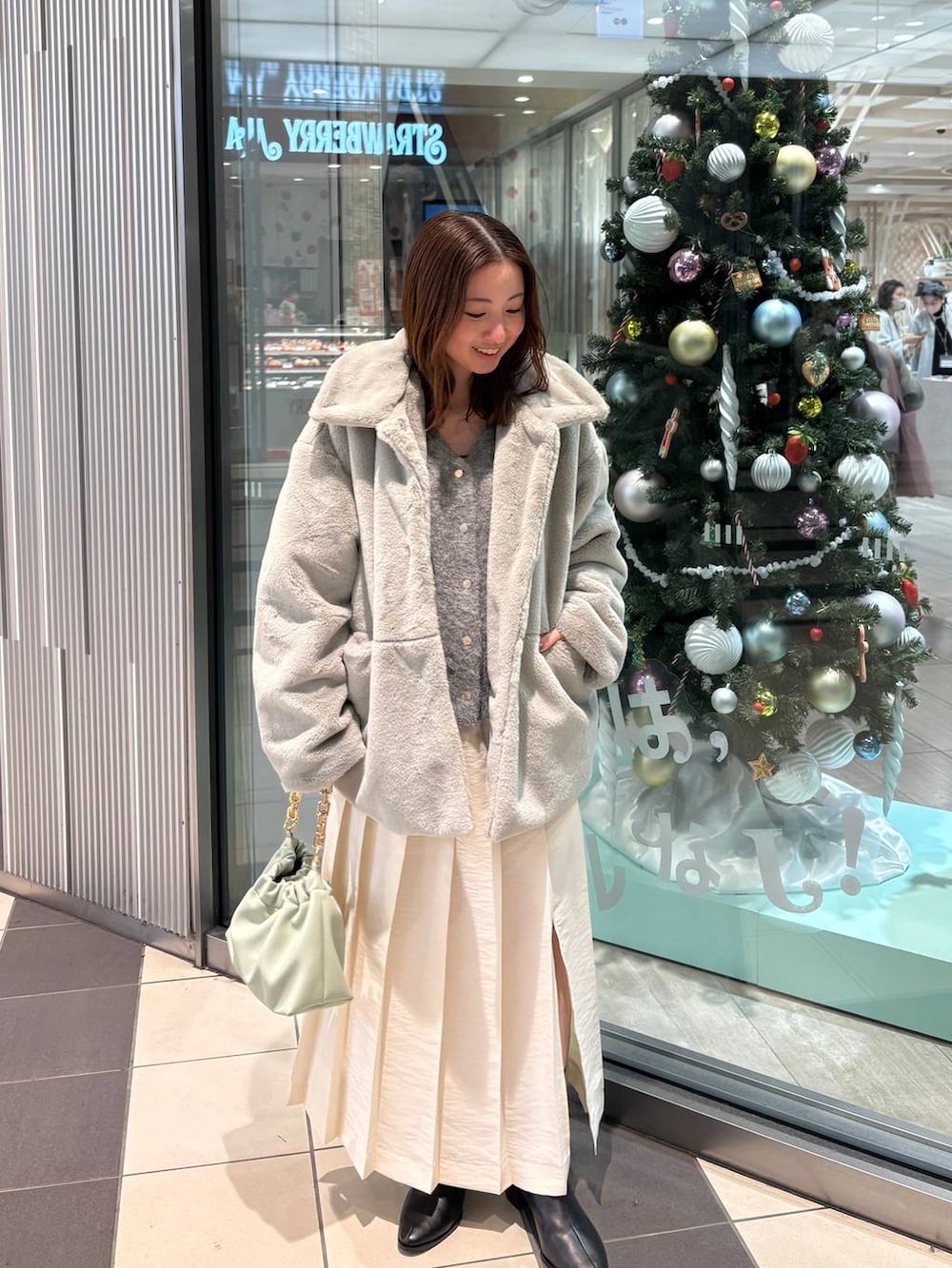 グレー系のその他アウター、グリーン系のショルダーバッグ、ホワイト系のスカートを着用したレディースの秋コーディネートの4枚目の写真