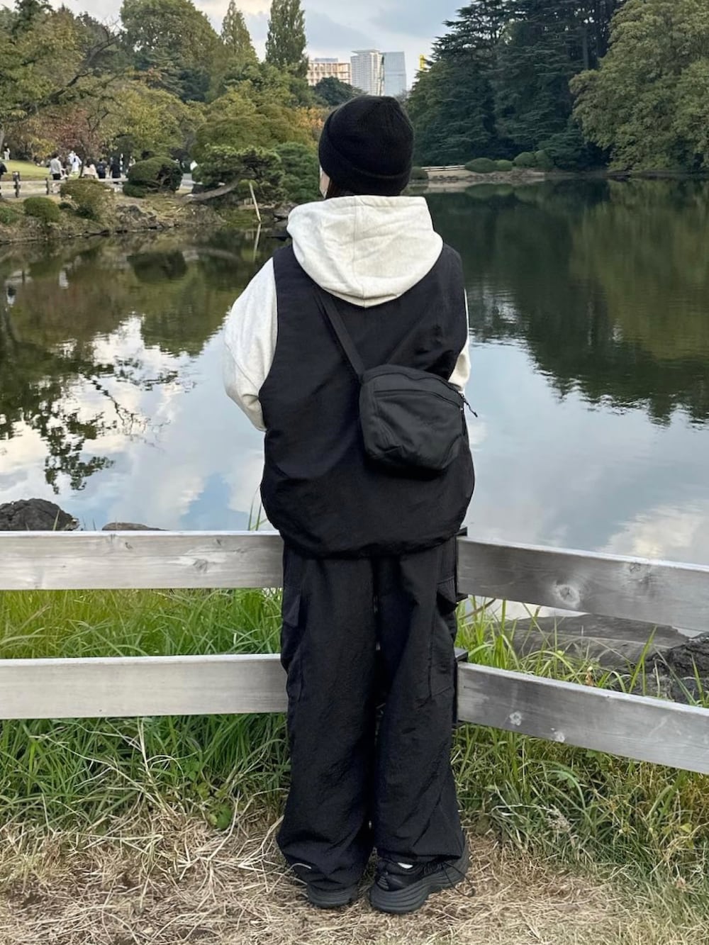 グレー系のパーカー、ブラック系のベスト、ブラック系のカーゴパンツを着用したレディースの秋コーディネートの2枚目の写真