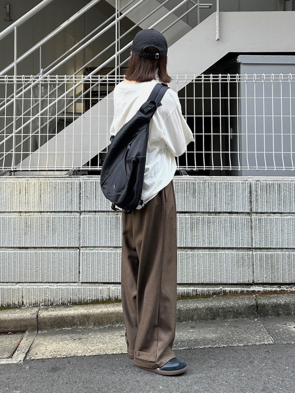 ホワイト系のTシャツ/カットソー、ブラウン系のスラックス、ブラック系のショルダーバッグを着用したレディースの夏コーディネートの3枚目の写真