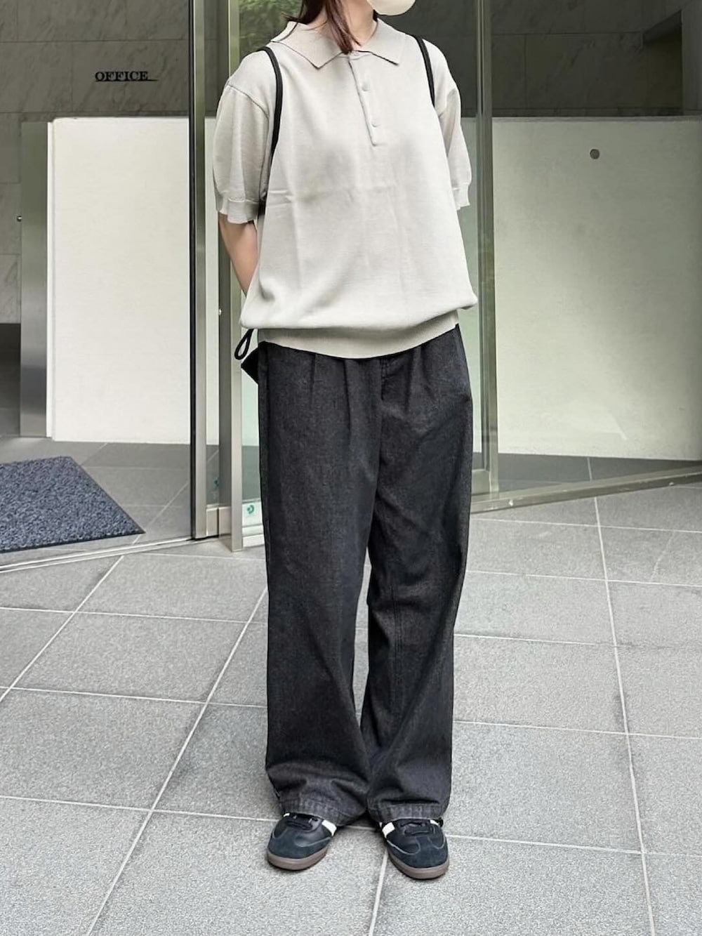 グレー系のポロシャツ、ブラック系のデニムパンツ、ブラック系のスニーカーを着用したレディースの夏コーディネートの2枚目の写真