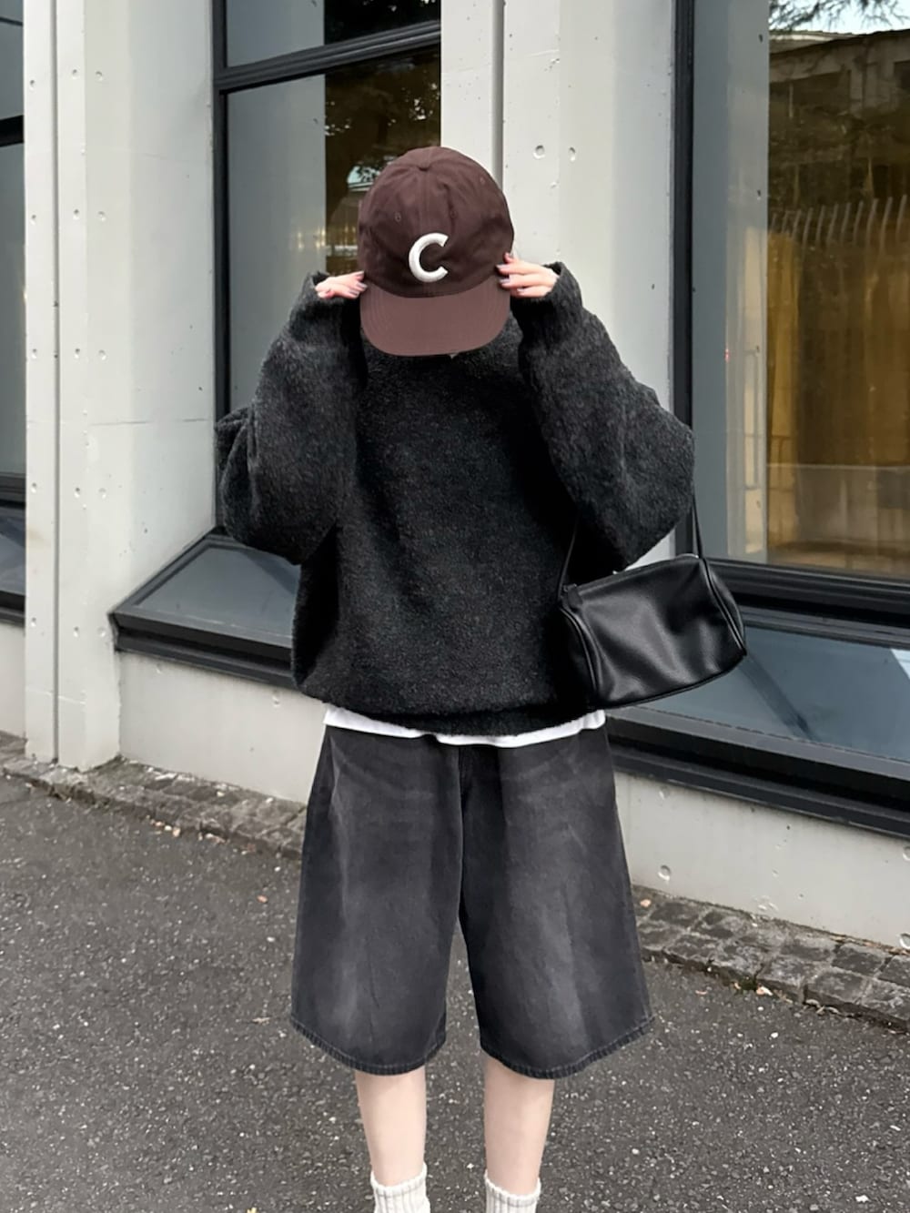 ブラック系のハンドバッグ、ブラック系のスニーカー、ブラック系のデニムパンツを着用したレディースの秋コーディネートの2枚目の写真