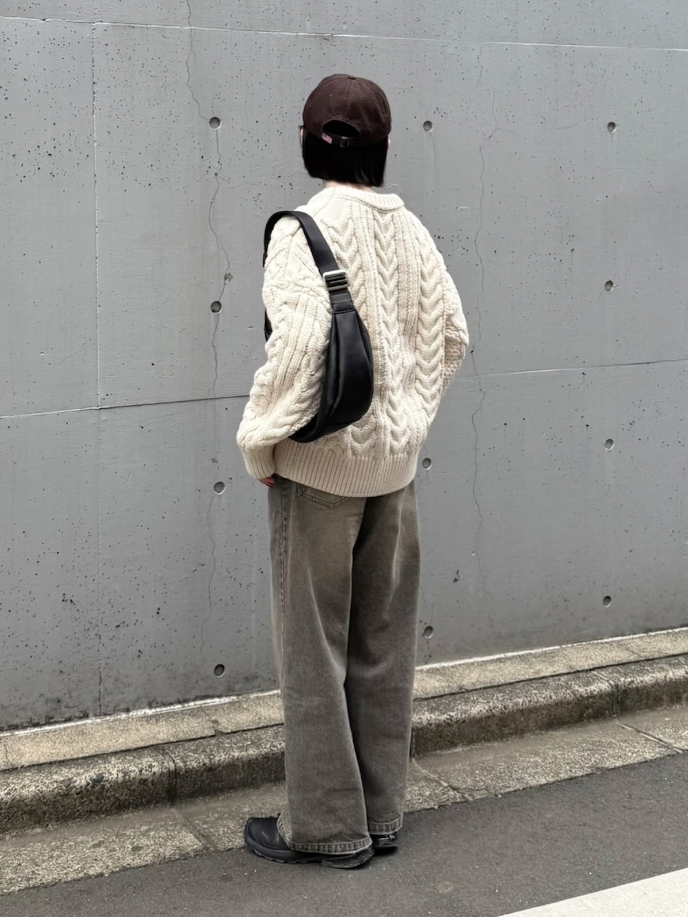 ブラック系のスニーカー、ホワイト系のニット/セーター、ブラック系のショルダーバッグを着用したレディースの冬コーディネートの2枚目の写真