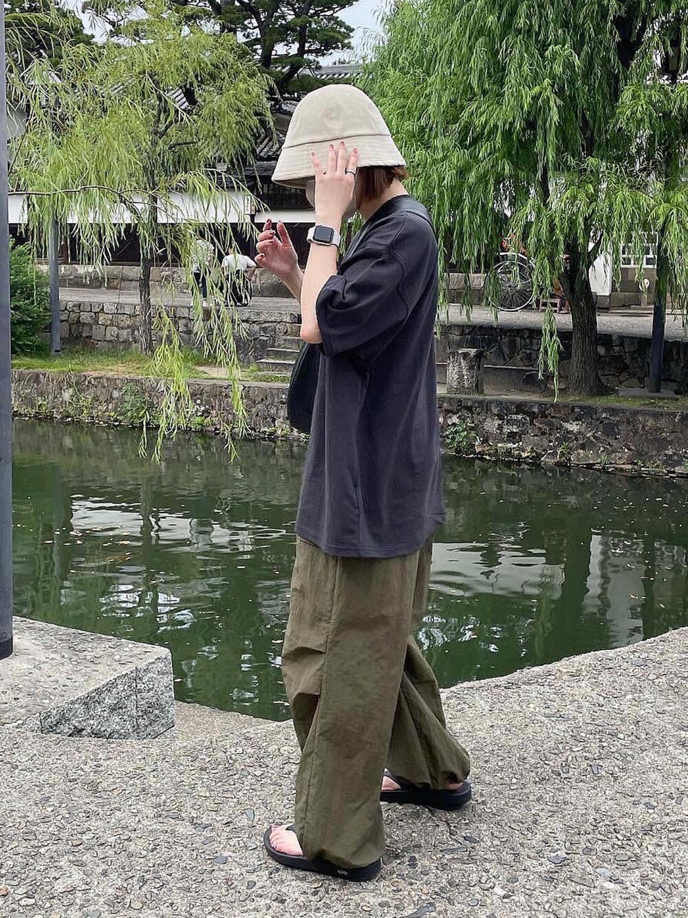 グレー系のTシャツ/カットソー、ブラック系のショルダーバッグ、ブラック系のサンダルを着用したレディースの夏コーディネートの2枚目の写真