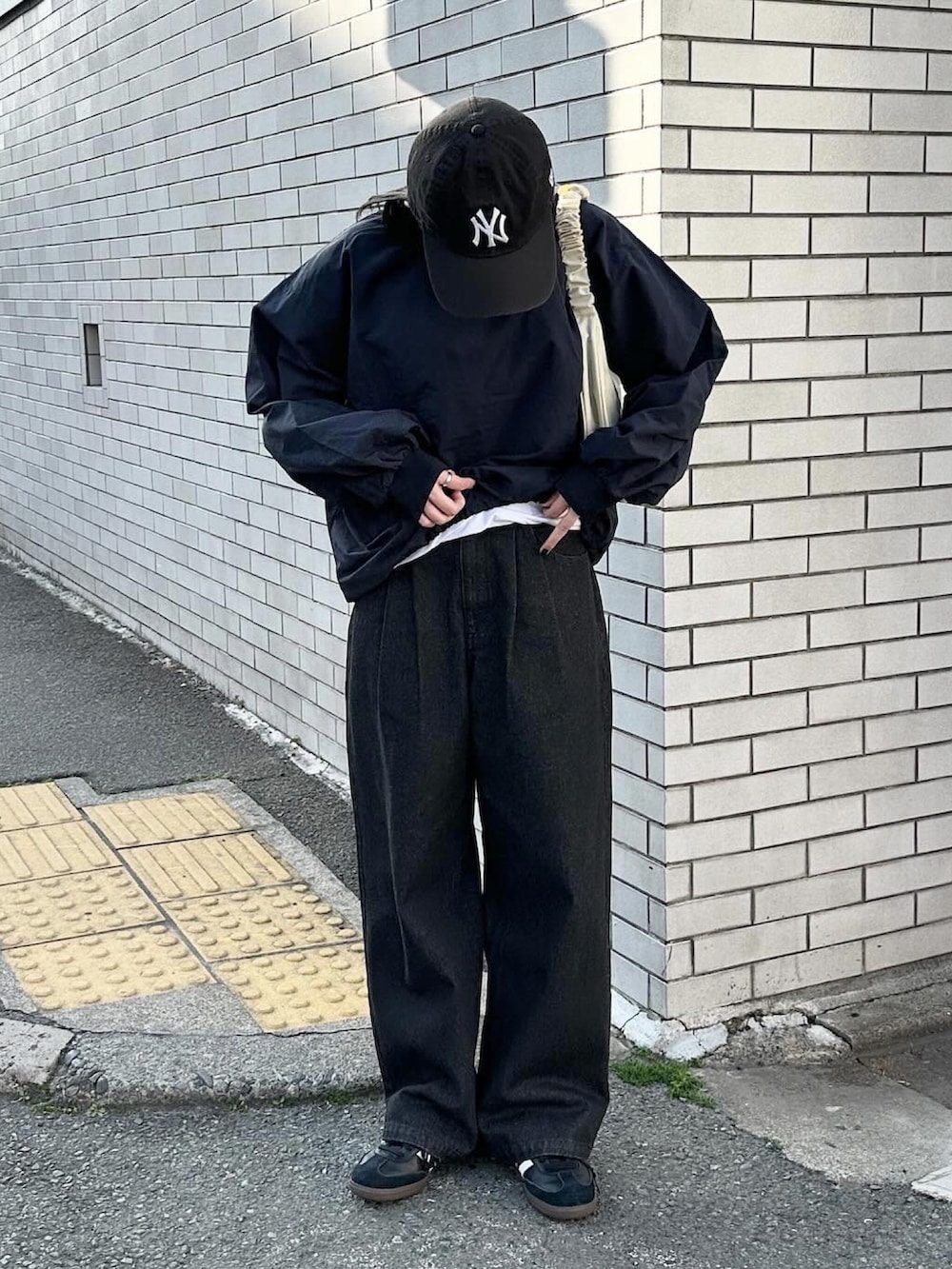 ブルー系のその他トップス、ブラック系のデニムパンツ、ベージュ系のハンドバッグを着用したレディースの春コーディネートの2枚目の写真