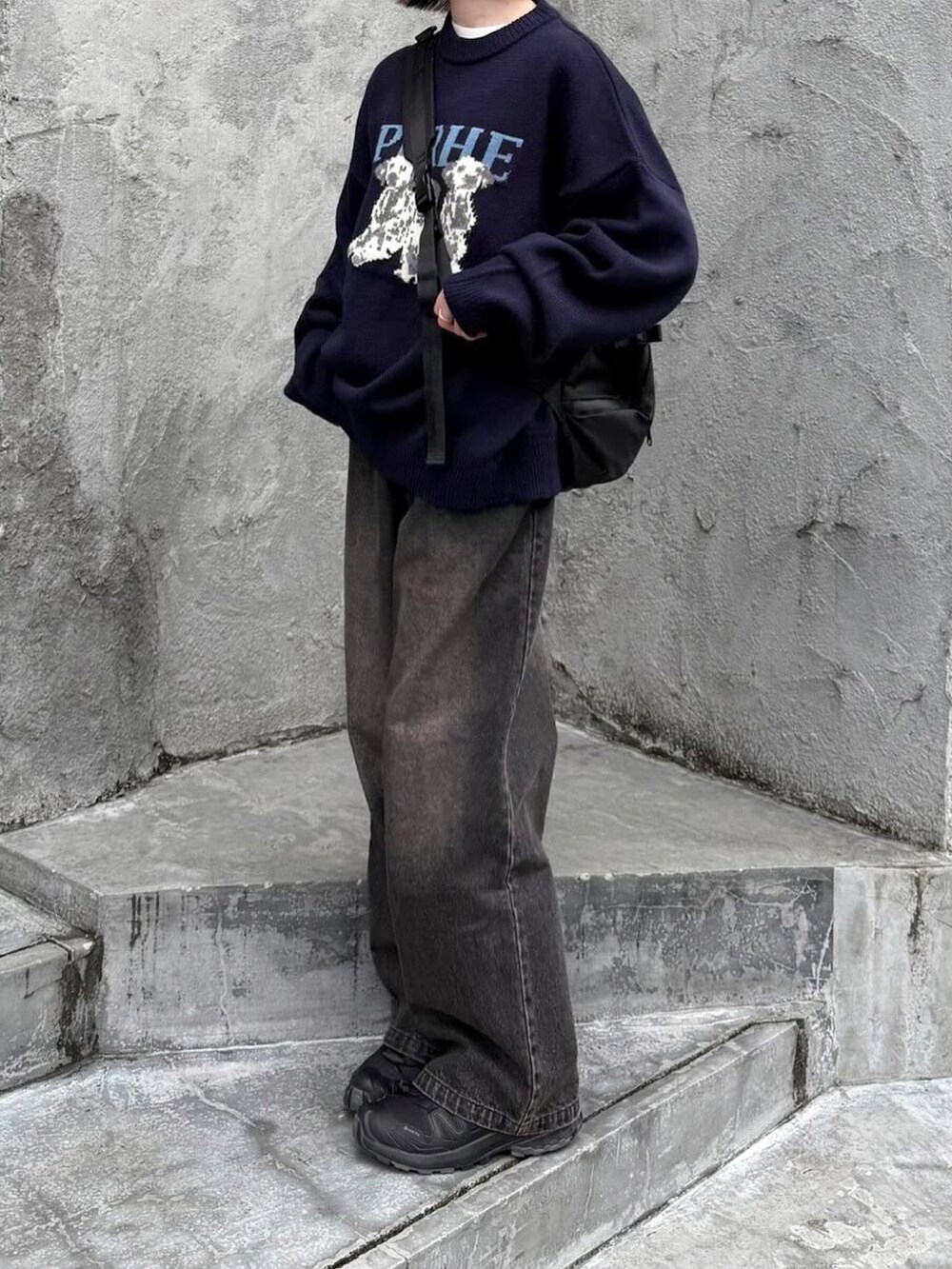 ブルー系のニット/セーター、ブラック系のデニムパンツ、ブラック系のショルダーバッグを着用したレディースの冬コーディネートの2枚目の写真