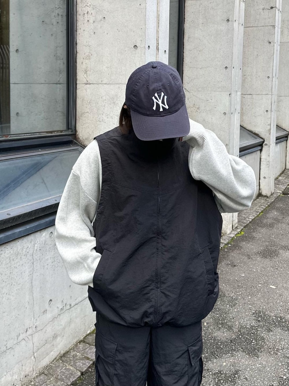 グレー系のニット/セーター、ブラック系のベスト、ブラック系のカーゴパンツを着用したレディースの秋コーディネートの3枚目の写真