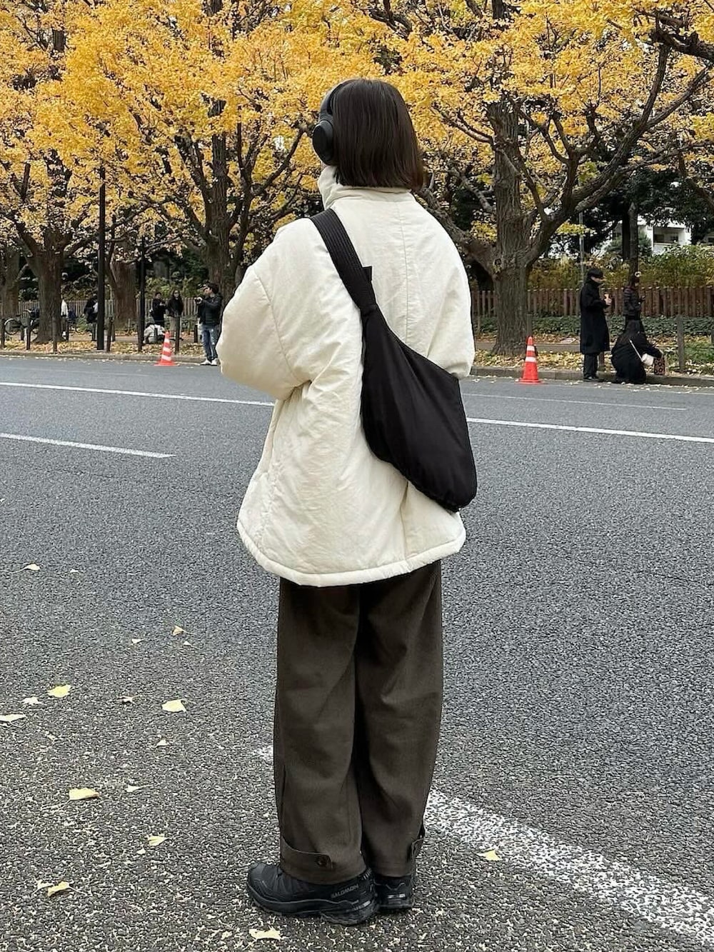 ホワイト系のその他アウター、ブラウン系のスラックス、ブラック系のショルダーバッグを着用したレディースの冬コーディネートの2枚目の写真