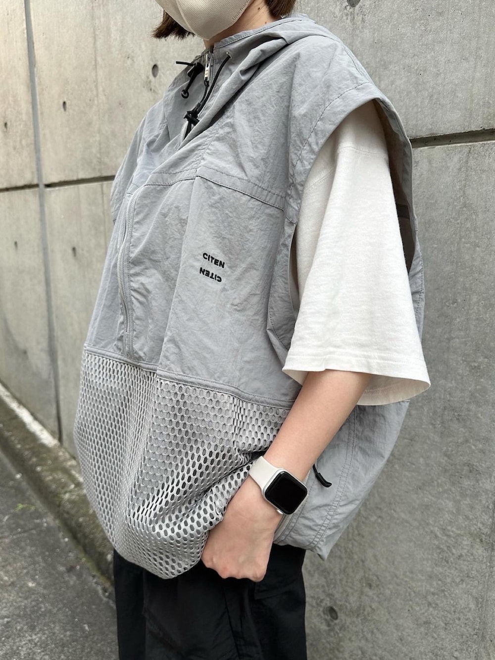 グレー系のベスト、ブラック系のその他パンツ、ホワイト系のスニーカーを着用したレディースの夏コーディネートの2枚目の写真