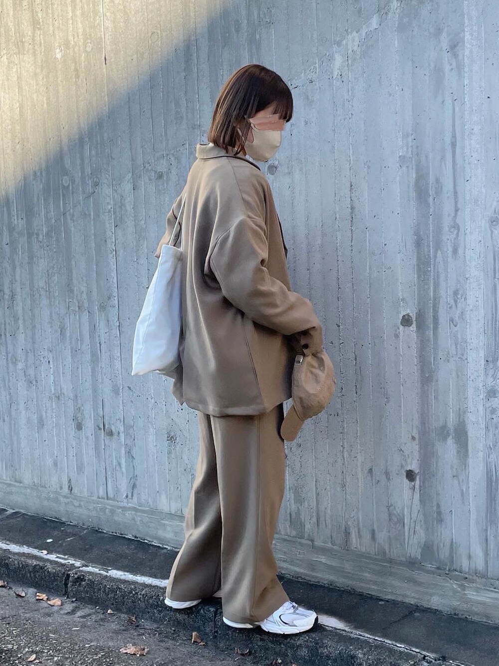 ベージュ系のテーラードジャケット、ベージュ系のニット/セーター、ホワイト系のトートバッグを着用したレディースの冬コーディネートの3枚目の写真