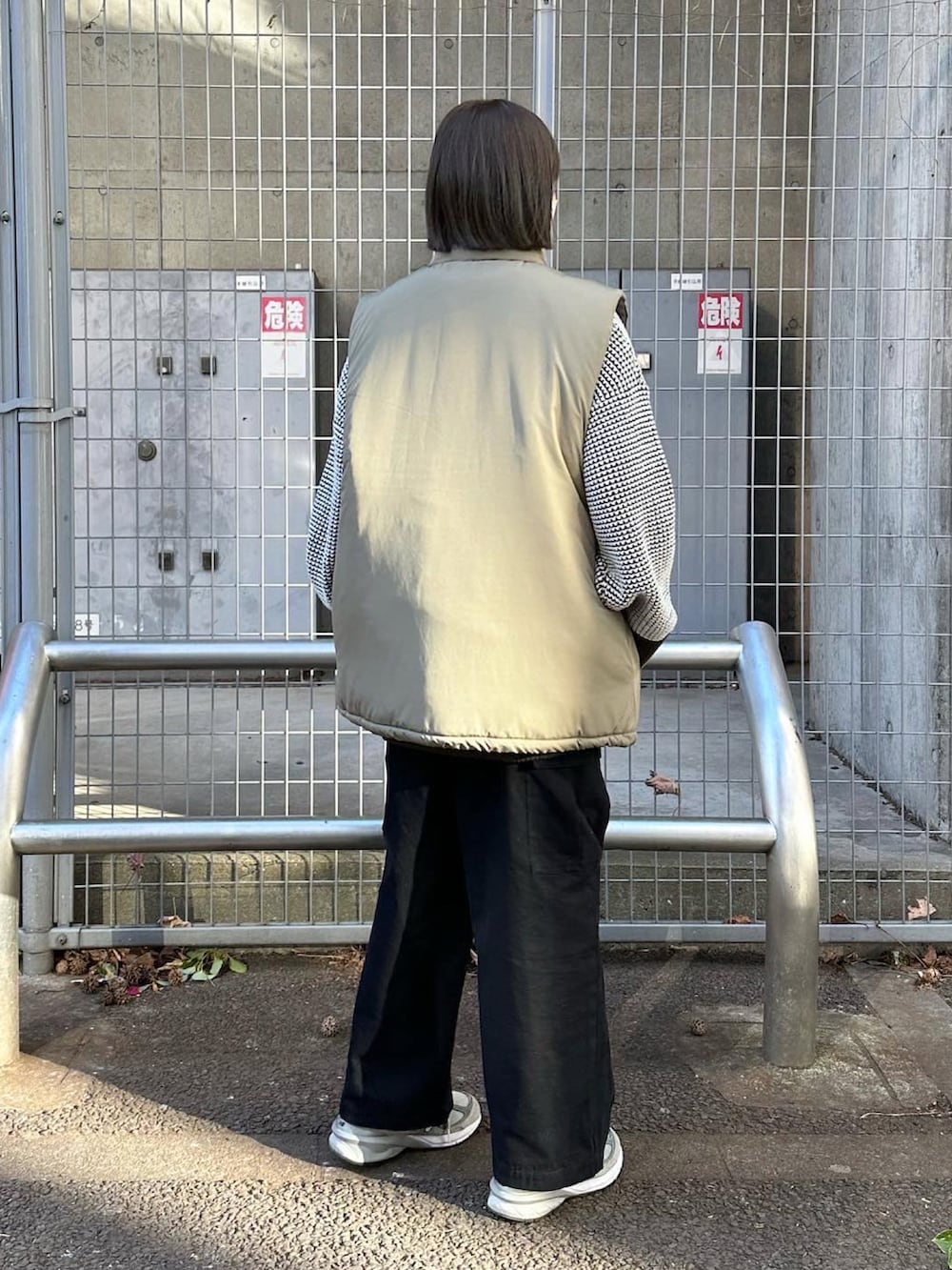 ベージュ系のベスト、グリーン系のニット/セーター、ブラック系のカーゴパンツを着用したレディースの冬コーディネートの3枚目の写真