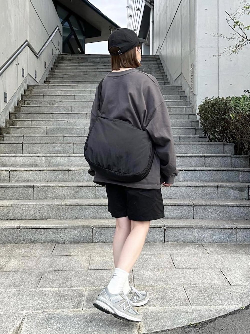 グレー系のTシャツ/カットソー、ブラック系のその他パンツ、ブラック系のショルダーバッグを着用したレディースの春コーディネートの2枚目の写真