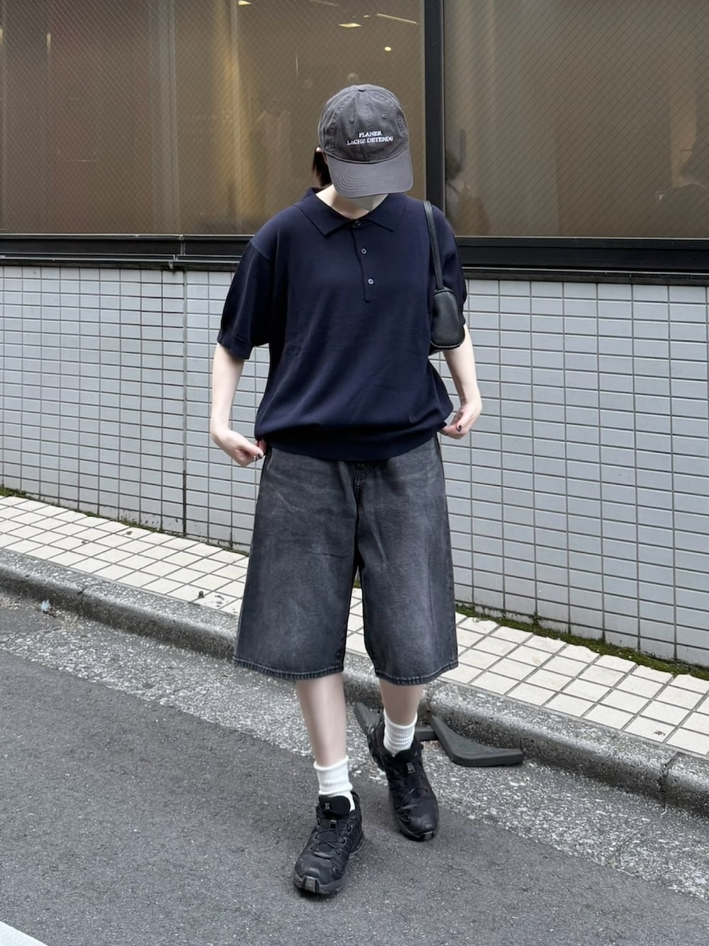 ブラック系のハンドバッグ、ブラック系のスニーカー、ブルー系のポロシャツを着用したレディースの夏コーディネートの2枚目の写真