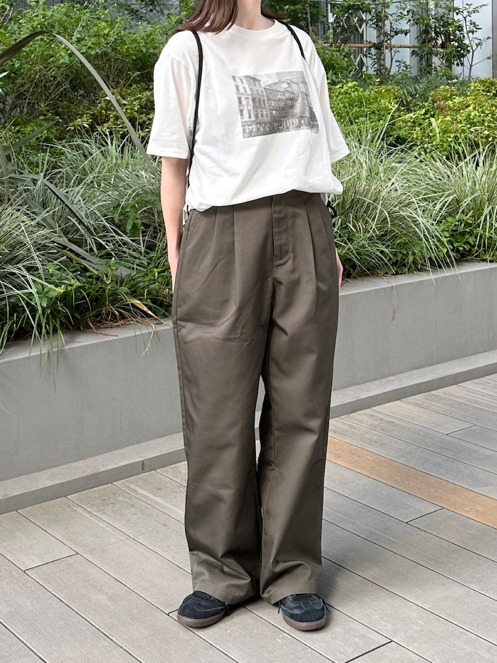 ホワイト系のTシャツ/カットソー、ブラウン系のチノパンツ、ブラック系のショルダーバッグを着用したレディースの夏コーディネートの2枚目の写真
