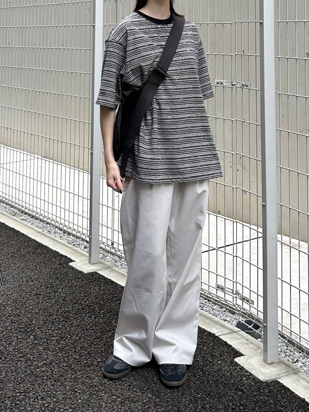ブラック系のTシャツ/カットソー、ホワイト系のチノパンツ、ブラック系のショルダーバッグを着用したレディースの夏コーディネートの3枚目の写真