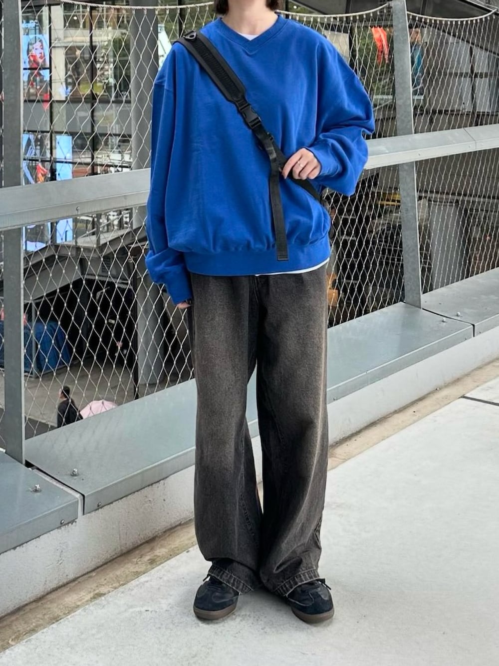 ブルー系のスウェット、ブラック系のデニムパンツ、ブラック系のショルダーバッグを着用したレディースの秋コーディネートの3枚目の写真