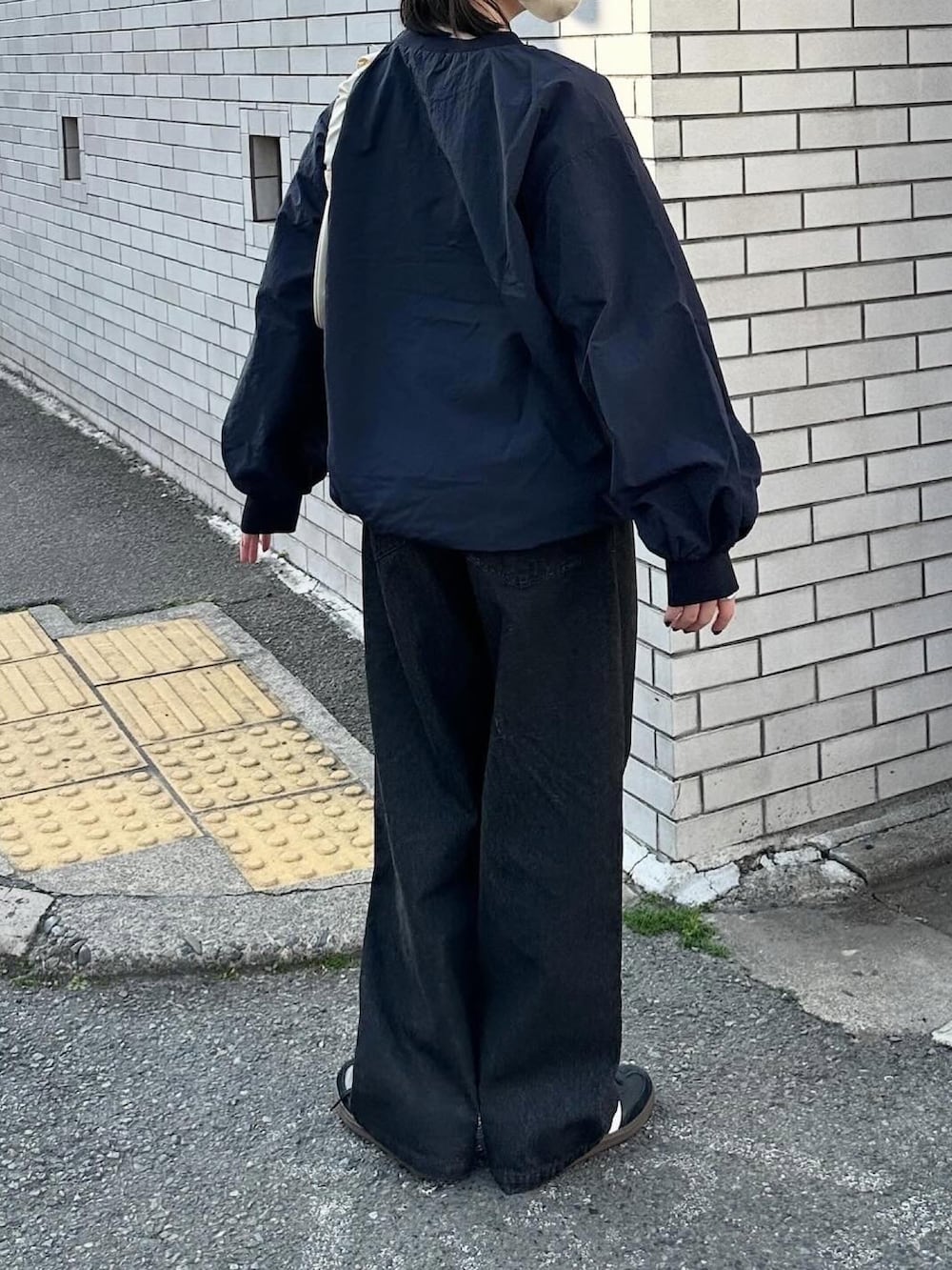 ブルー系のその他トップス、ブラック系のデニムパンツ、ベージュ系のハンドバッグを着用したレディースの春コーディネートの4枚目の写真