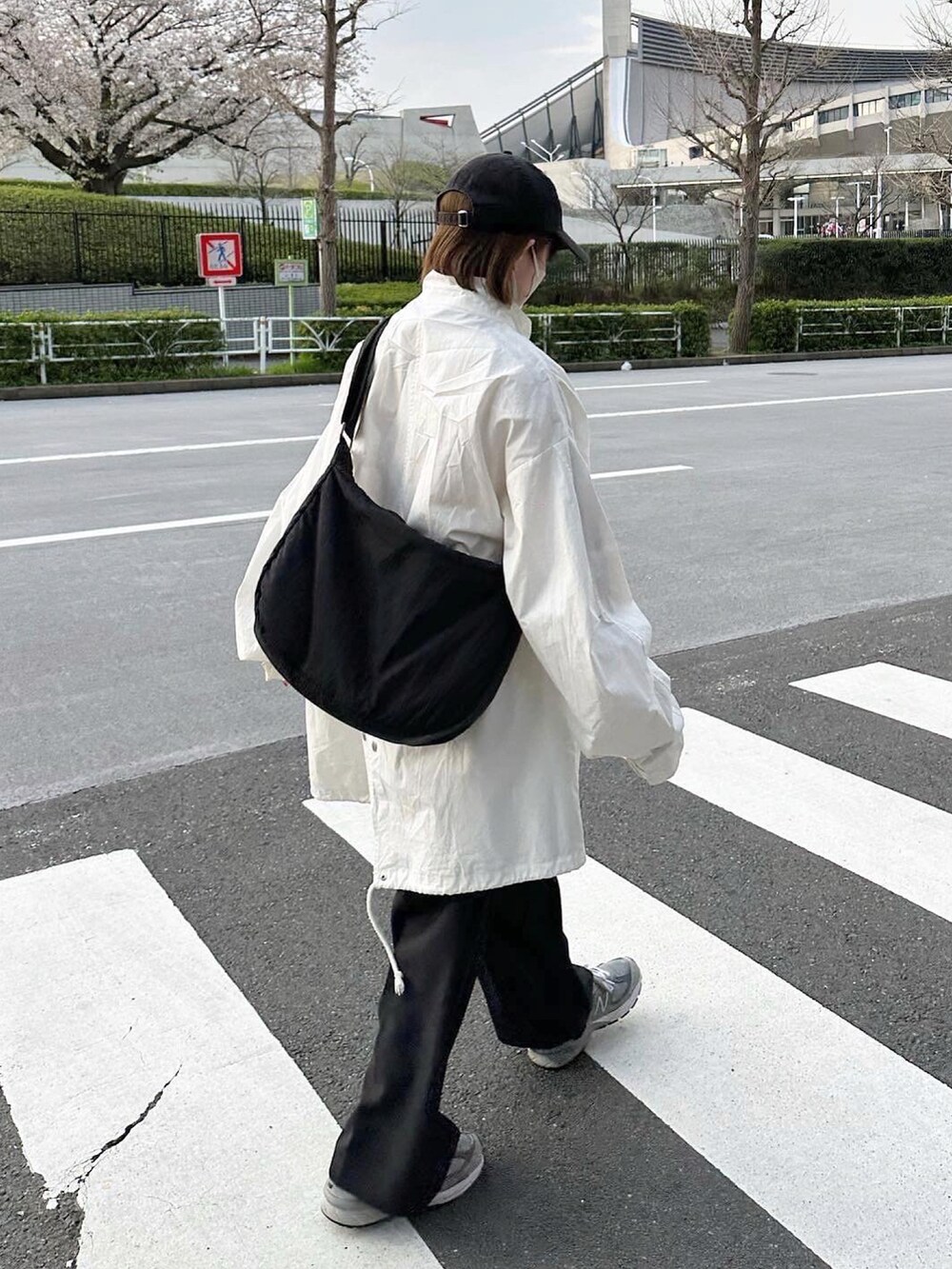 ホワイト系のマウンテンパーカー、ブラック系のスラックス、ブラック系のショルダーバッグを着用したレディースの春コーディネートの2枚目の写真