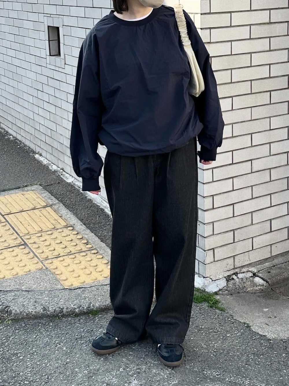 ブルー系のその他トップス、ブラック系のデニムパンツ、ベージュ系のハンドバッグを着用したレディースの春コーディネートの3枚目の写真