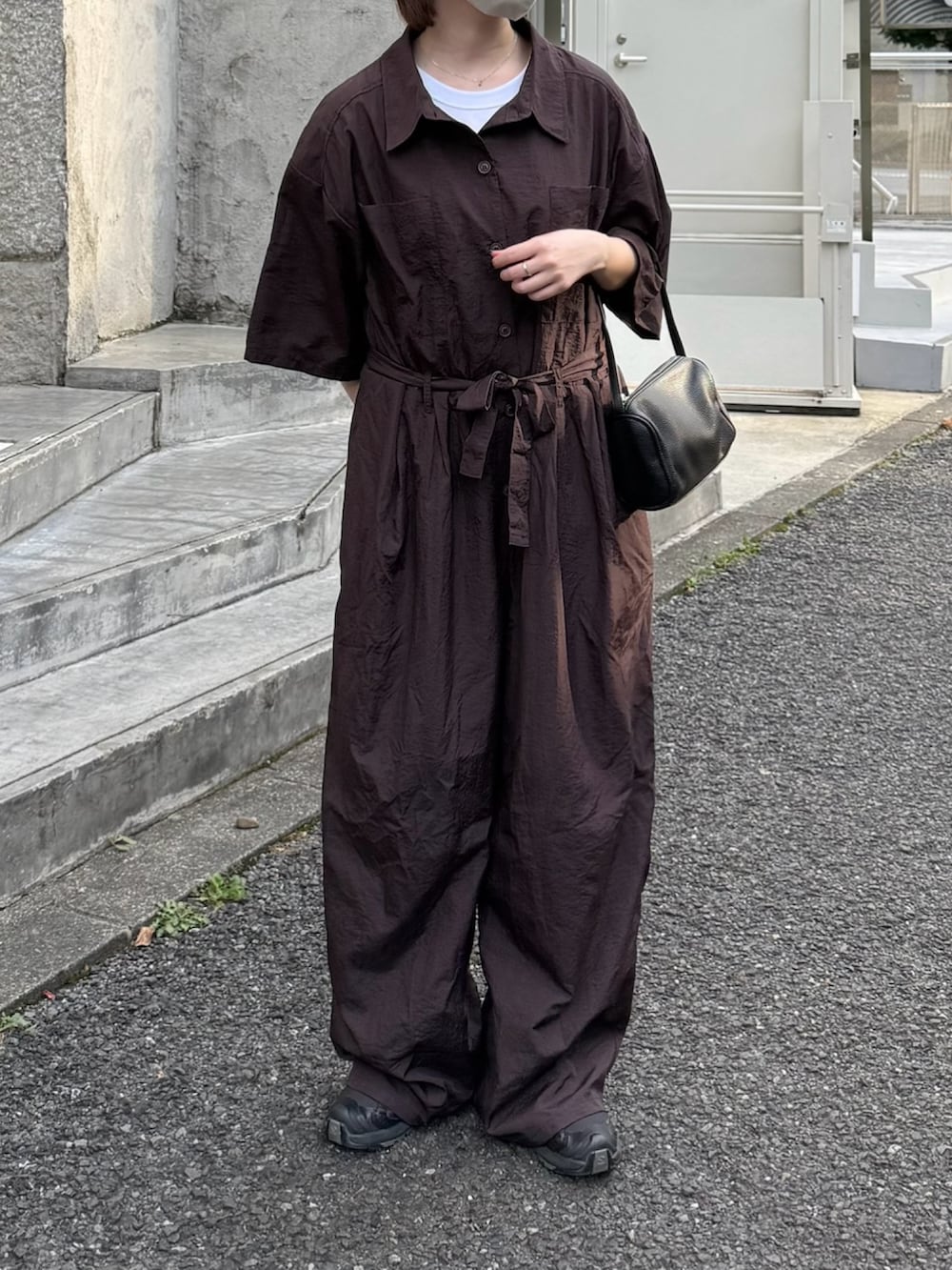 ブラック系のハンドバッグ、ブラウン系のつなぎ/オールインワン、ブラック系のスニーカーを着用したレディースの夏コーディネートの2枚目の写真