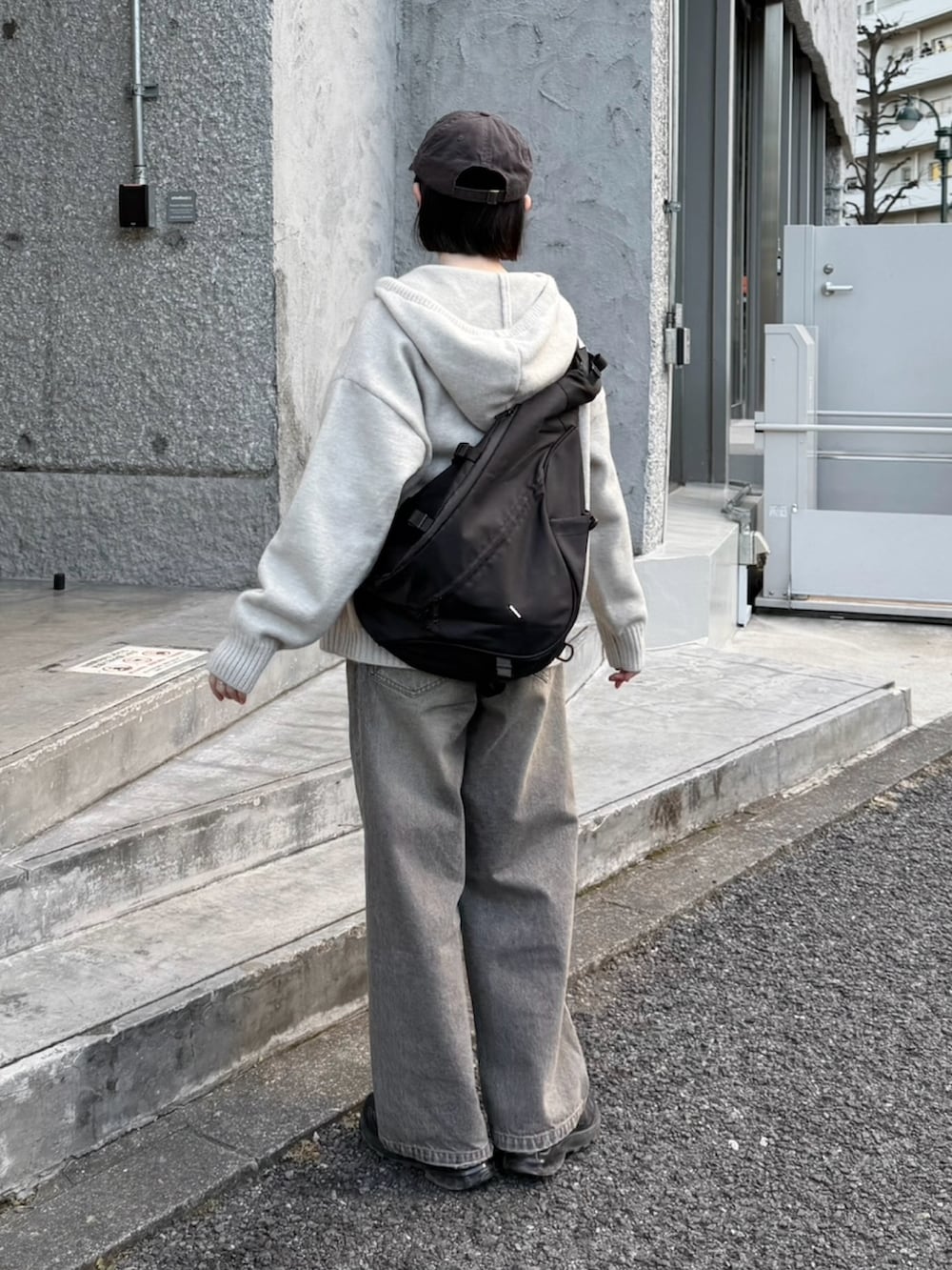 グレー系のニット/セーター、ブラック系のTシャツ/カットソー、ブラック系のスニーカーを着用したレディースの冬コーディネートの2枚目の写真