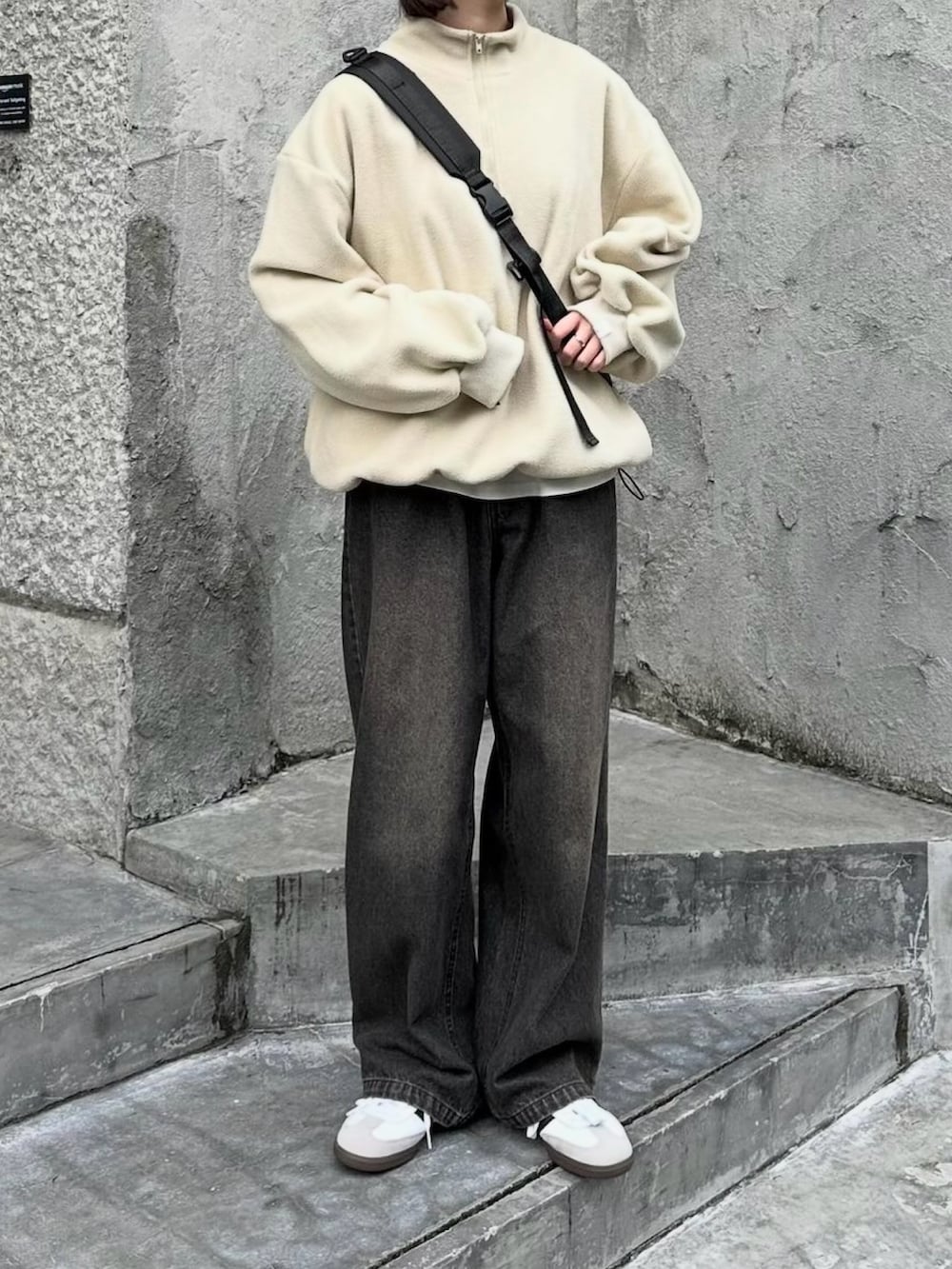 ホワイト系のスウェット、ブラック系のデニムパンツ、ブラック系のショルダーバッグを着用したレディースの秋コーディネートの3枚目の写真