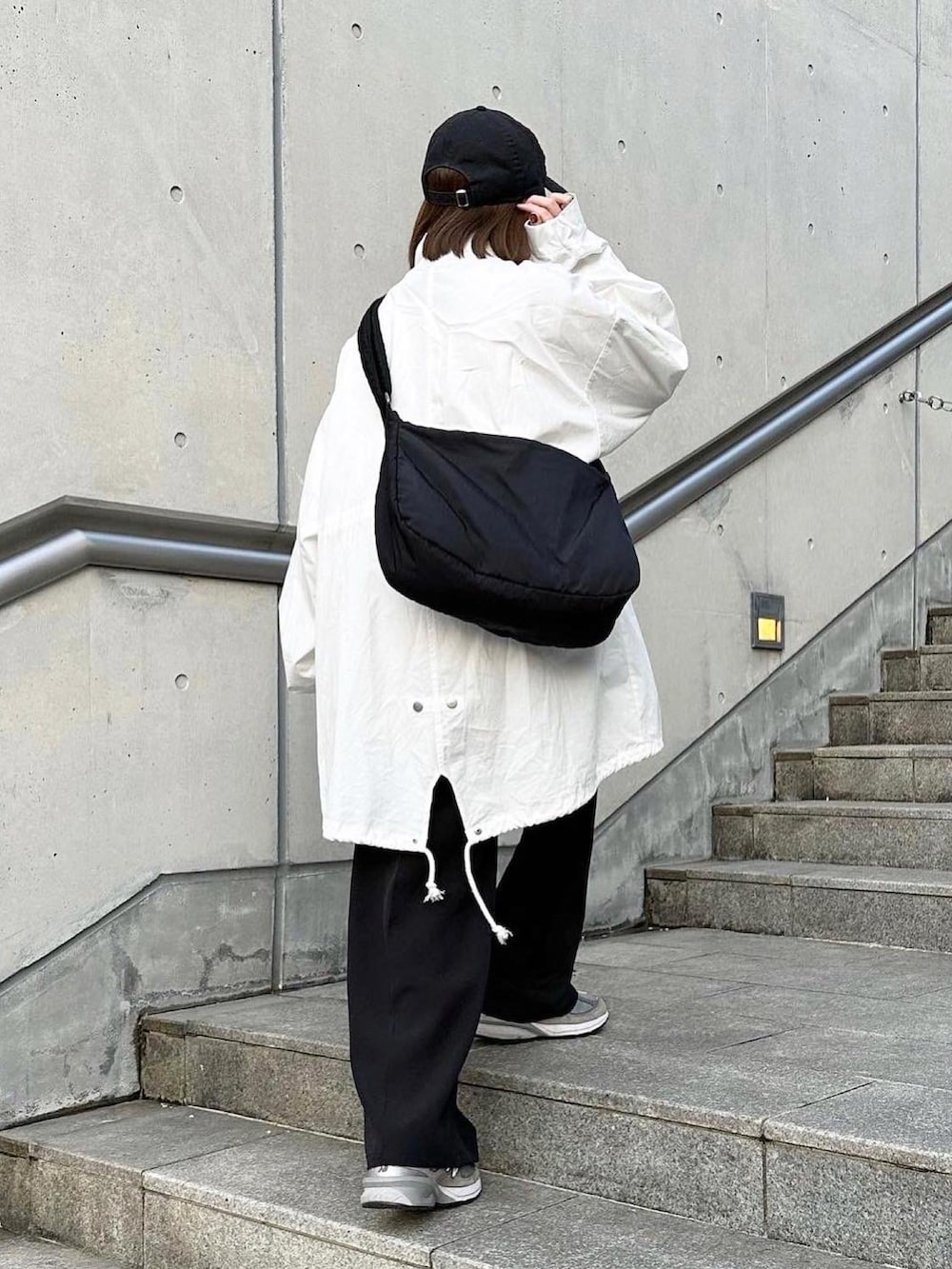 ホワイト系のマウンテンパーカー、ブラック系のスラックス、ブラック系のショルダーバッグを着用したレディースの春コーディネートの3枚目の写真