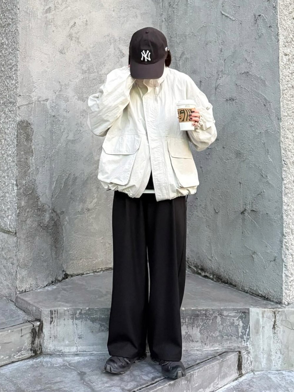 ホワイト系のマウンテンパーカー、ブラック系のスラックス、ブラック系のスニーカーを着用したレディースの冬コーディネートの2枚目の写真