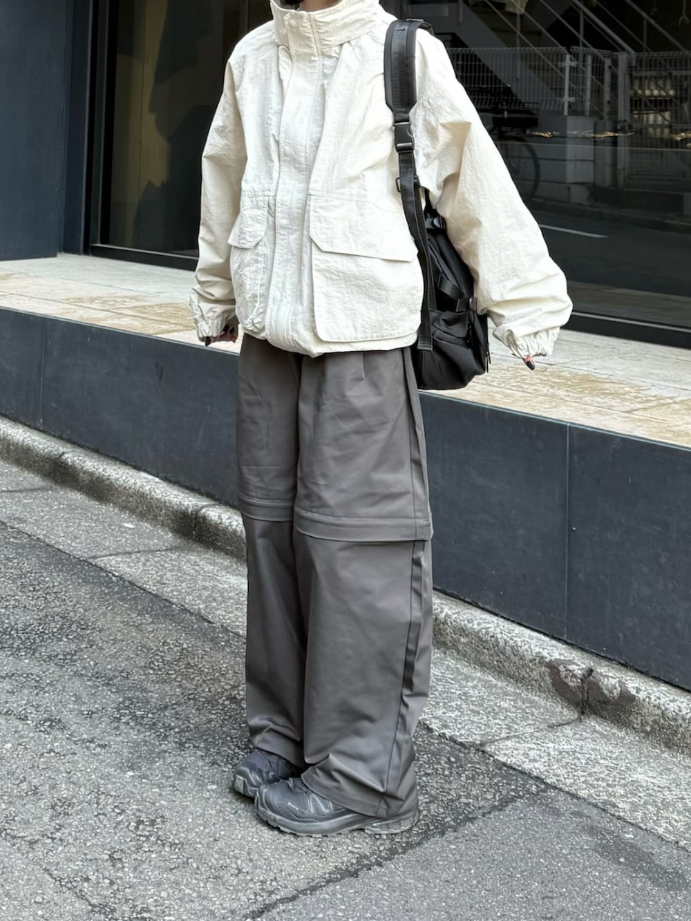 ブラック系のスニーカー、ホワイト系のマウンテンパーカー、ブラック系のショルダーバッグを着用したレディースの春コーディネートの2枚目の写真
