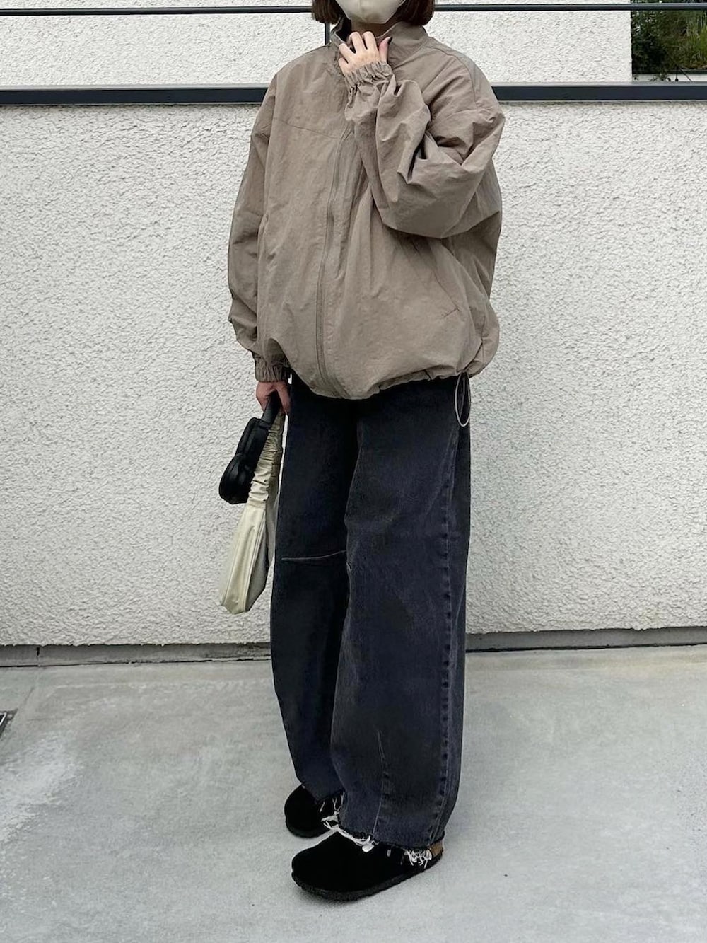 ベージュ系のブルゾン、ブラック系のデニムパンツ、ブラック系のサンダルを着用したレディースの秋コーディネートの2枚目の写真