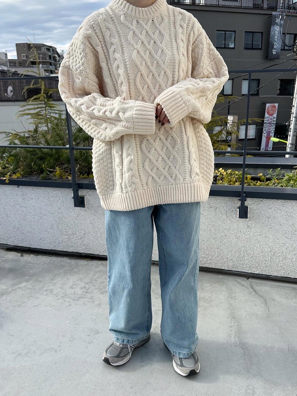 ブラック系のステンカラーコート、ホワイト系のニット/セーター、ブルー系のデニムパンツを着用したレディースの冬コーディネートの2枚目の写真