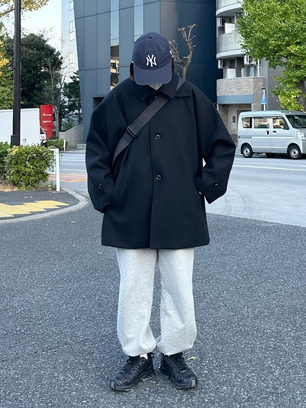 ブラック系のステンカラーコート、グレー系のスウェットパンツ、ブラック系のショルダーバッグを着用したレディースの秋コーディネートの3枚目の写真