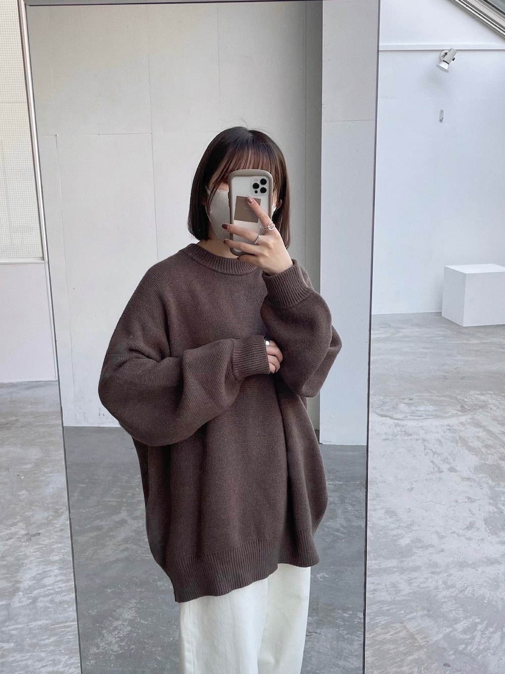 ホワイト系のデニムパンツ、ブラック系のスニーカー、ブラウン系のニット/セーターを着用したレディースの秋コーディネートの2枚目の写真