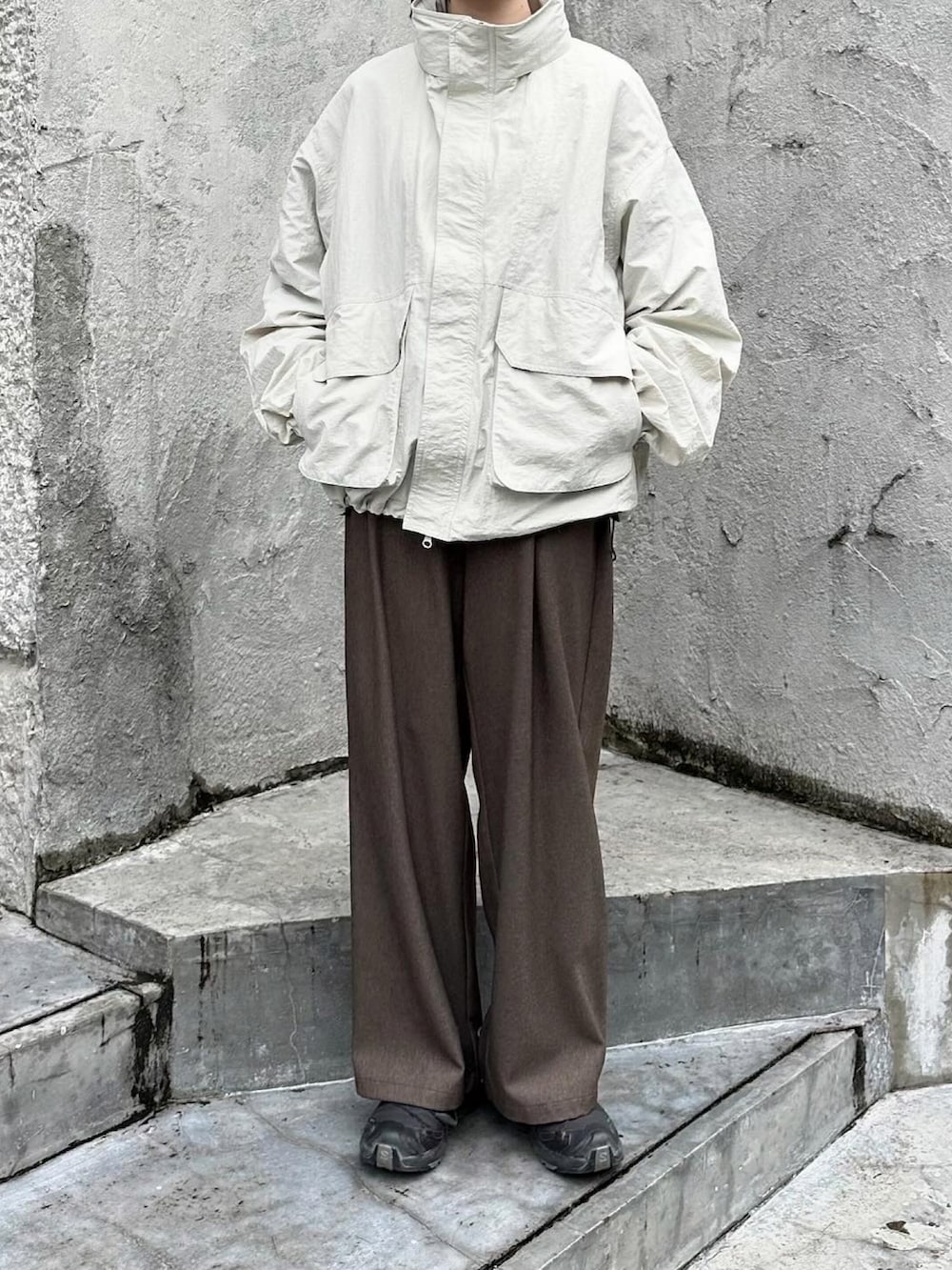 ホワイト系のマウンテンパーカー、ブラウン系のスラックス、ブラック系のスニーカーを着用したレディースの冬コーディネートの2枚目の写真