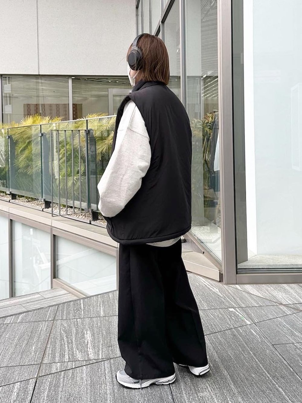 ブラック系のベスト、グレー系のスウェット、ブラック系のスラックスを着用したレディースの春コーディネートの2枚目の写真