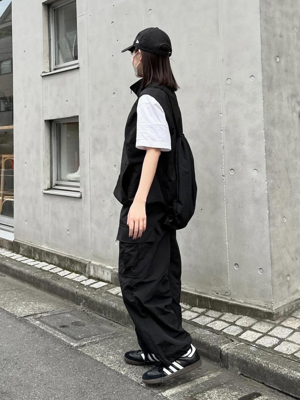 ブラック系のベスト、ブラック系のカーゴパンツ、ブラック系のスニーカーを着用したレディースの春コーディネートの2枚目の写真