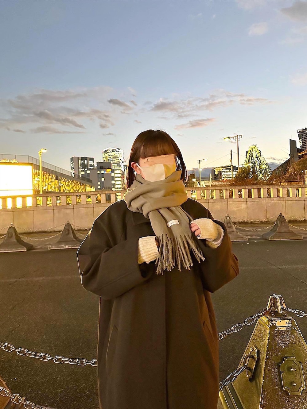 ブラウン系のステンカラーコート、グレー系のスニーカー、グレー系のマフラーを着用したレディースの冬コーディネートの2枚目の写真