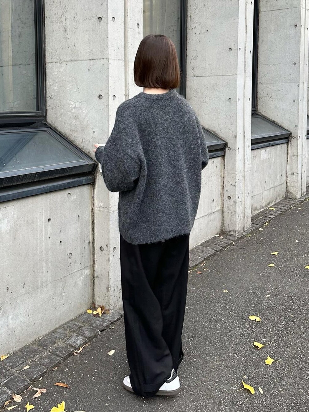 グレー系のニット/セーター、ブラック系のスラックス、ホワイト系のスニーカーを着用したレディースの冬コーディネートの2枚目の写真