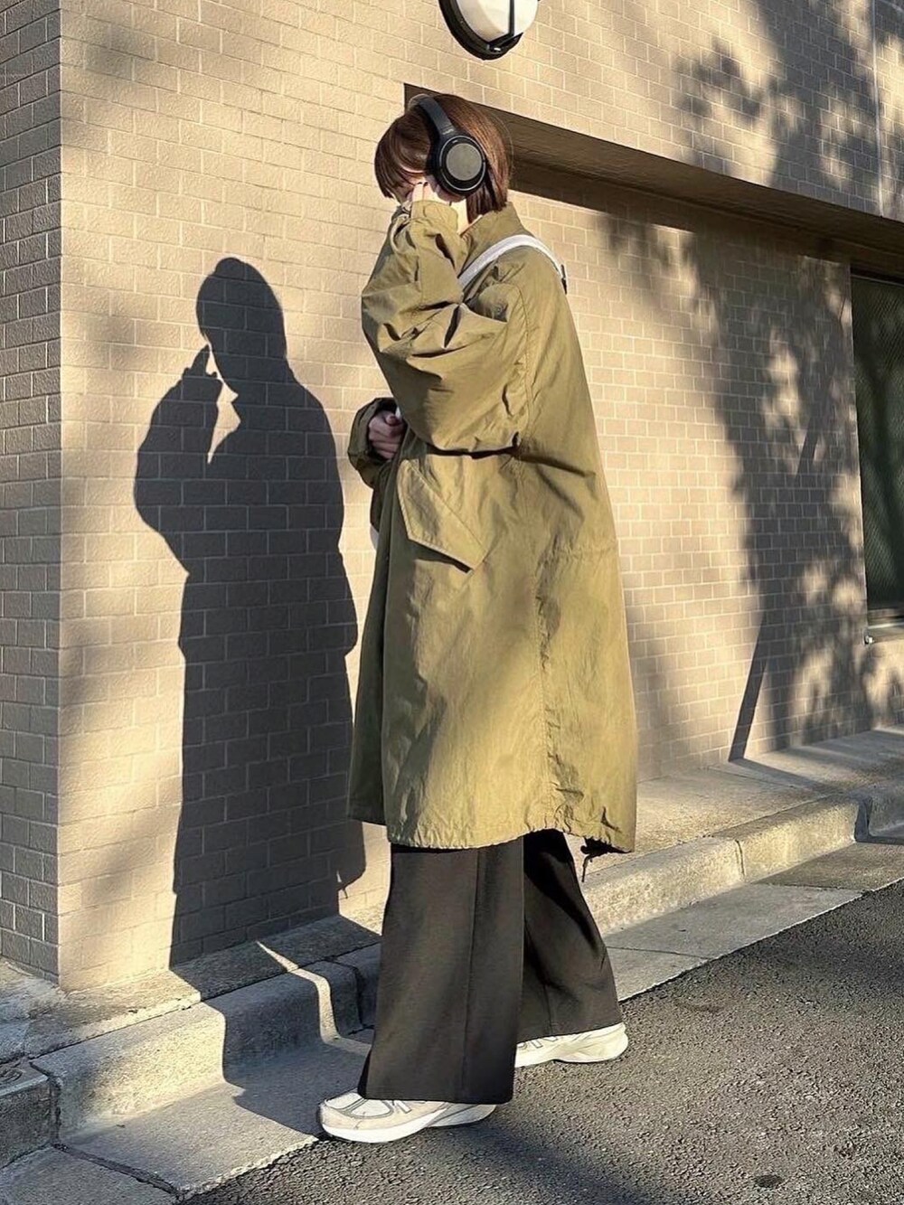 グリーン系のモッズコート、ブラウン系のニット/セーター、ブラック系のスラックスを着用したレディースの春コーディネートの2枚目の写真